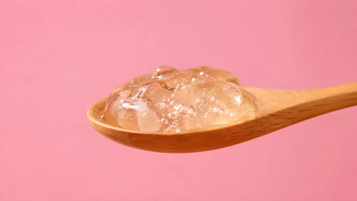 Transparentes Gel auf einem Holzlöffel vor Rosa