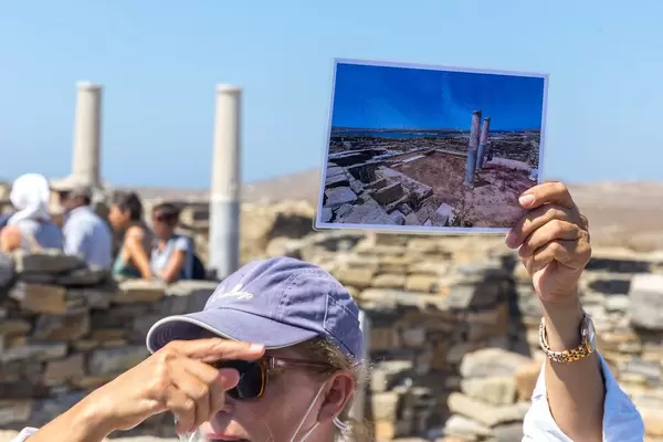 Travel guide at the archaeological site of Delos, Greece, shows a photo with ruins and columns
