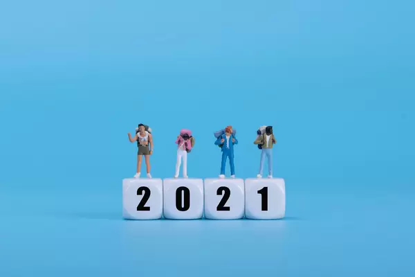 Travelers standing on white blocks with 2021 text on blue background