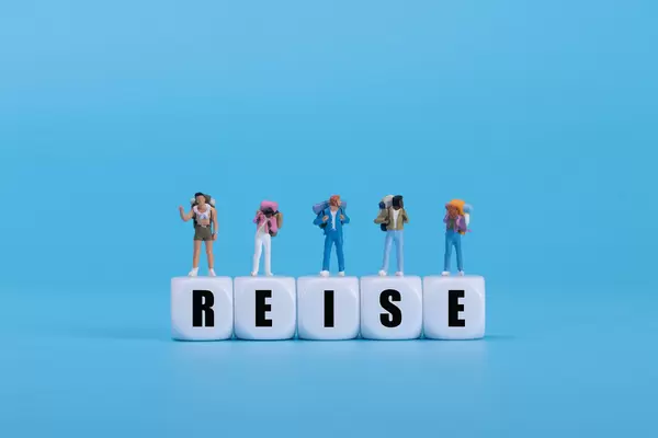 Travelers standing on white blocks with Reise text on blue background