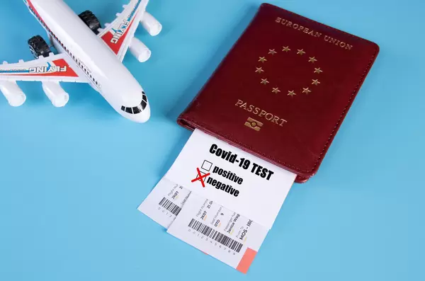 Traveling during COVID-19 virus, passport with airline ticket, covid-19 test card with "negative" mark and plane on blue background