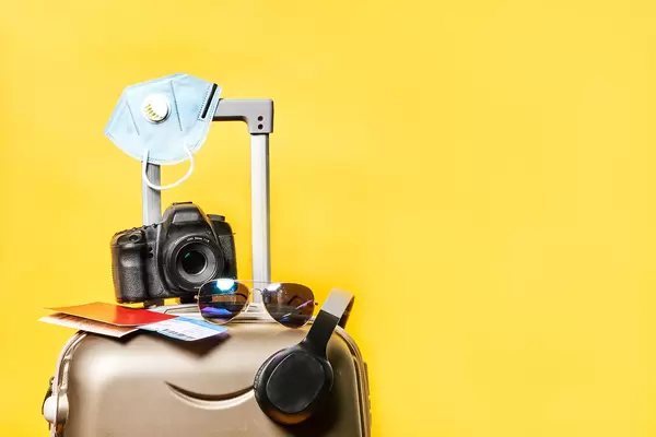 Traveling in pandemic - travel bag with document, ticket, sunglasses, camera and headset