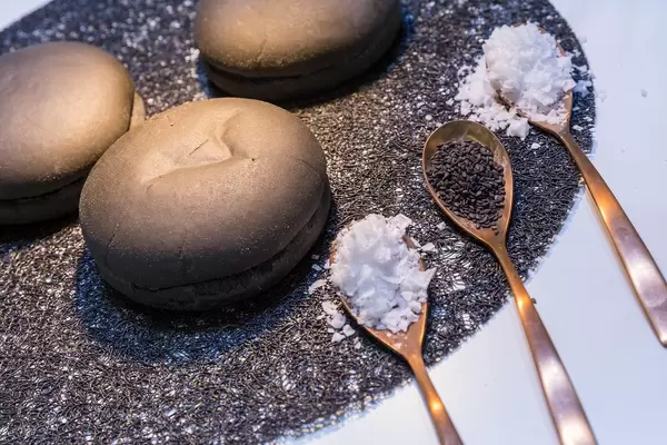 Trendy black hamburger buns on display with ingredients on spoons