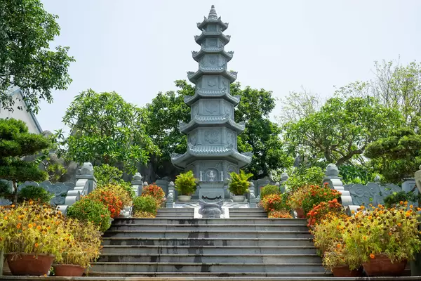 Treppen führen zu einem Steinturm mit kleinem Altar und vielen Pflanzen bei der Linh Ung Pagode auf der Son Tra Halbinsel in Da Nang, Vietnam