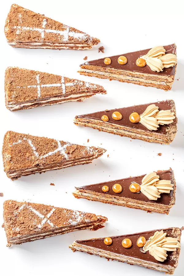 Triangular pieces of chocolate napoleon and nut cake on white background