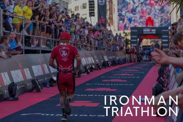 Triathlete runs the last meters of the marathon during the Ironman Triathlon, with thunderous applause from spectators