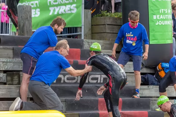 Triathlete runs up a wooden staircase after the swimming competition during the Ironman 70.3