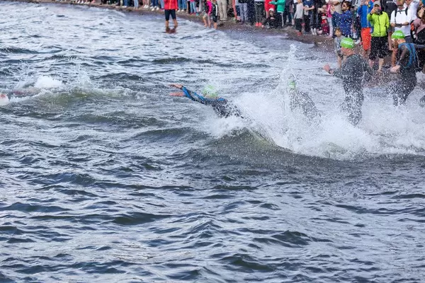 Triathleten bei der Ironman-Sportart Schwimmen im Süden von Finnland am Vesijärvisee, spritzen beim Sprung ins Wasser