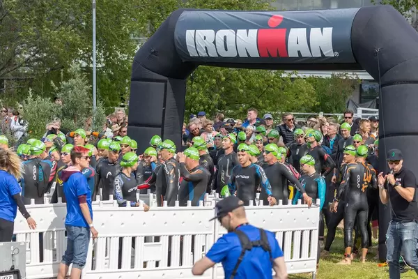 Triathleten stehen am Ufer des Vesijärvi-See bei Lahti, an der Ironman-Startlinie, um den Triathlon-Wettkampf zu beginnen