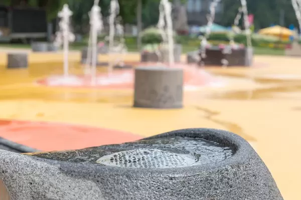 Trinkbrunnen am Spielplatz, Fontäne im Hintergrund
