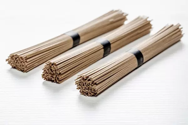 Trockene und rohe Japanische Soba Nudelstäbchen vor weißem Holzhintergrund