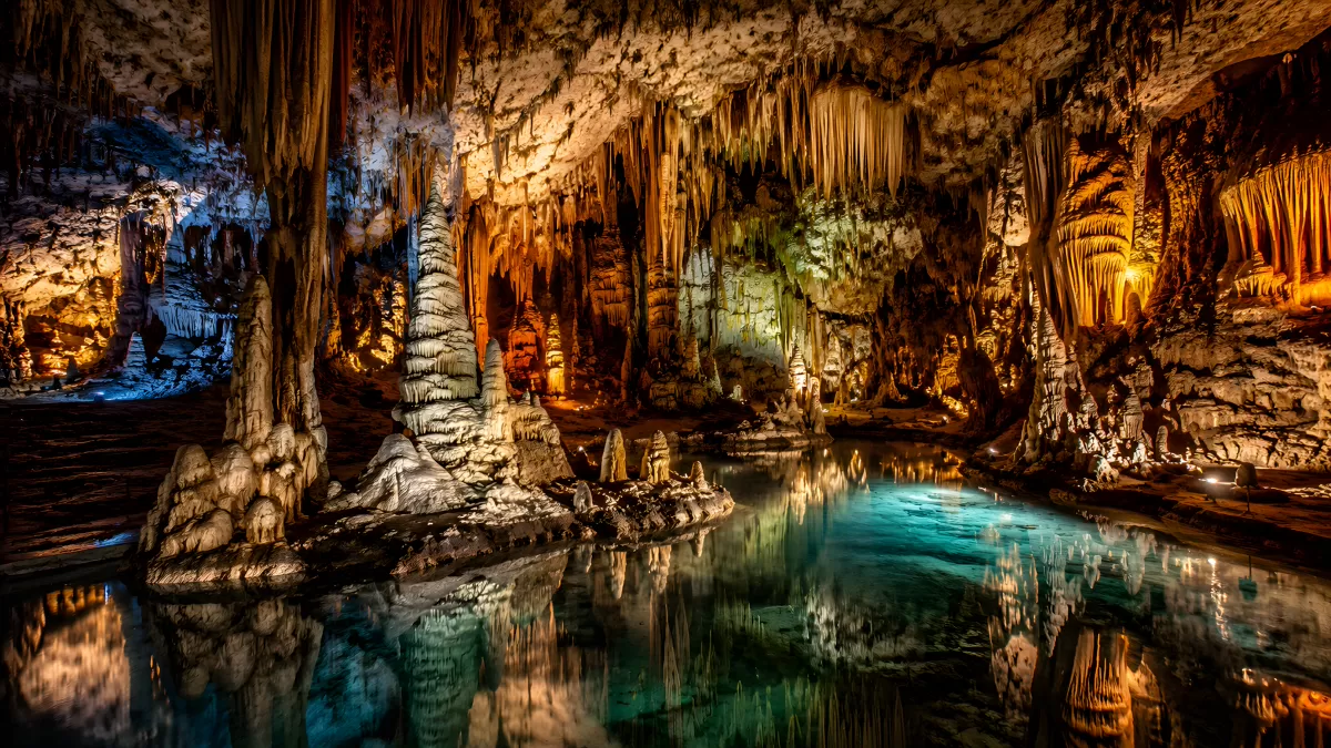 Tropfsteinhöhle mit Bergsee und bunter Beleuchtung