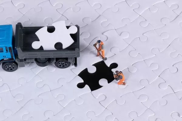 Truck with missing puzzle piece and two miniature workers