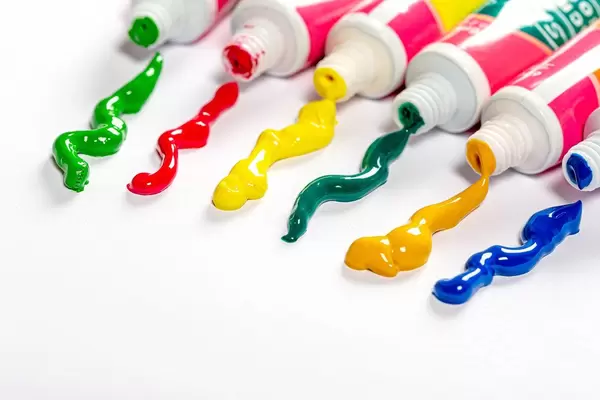 Tubes of colorful oil paint on white paper