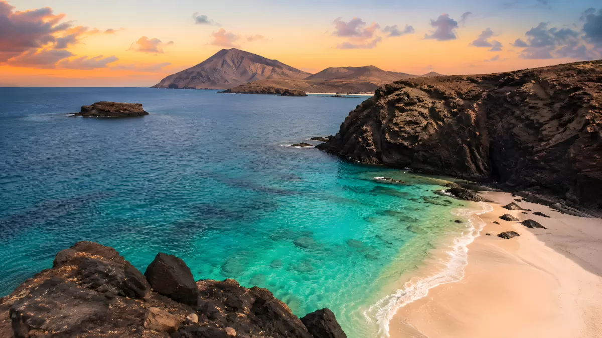 Türkisfarbene Bucht mit Sandstrand bei Sonnenuntergang