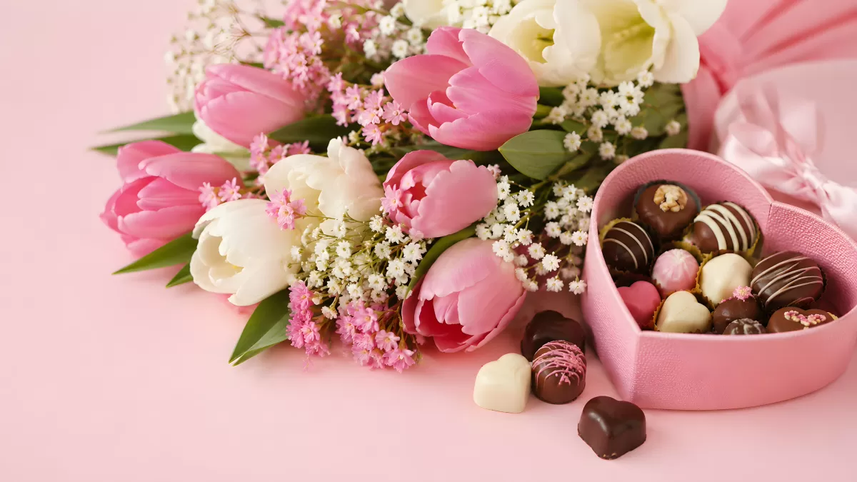 Tulpenstrauß mit rosa Herzdose voller Pralinen