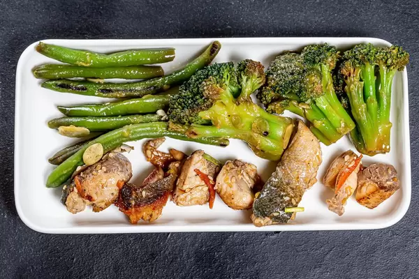 Tuna with asparagus and broccoli on a white plate. Top view