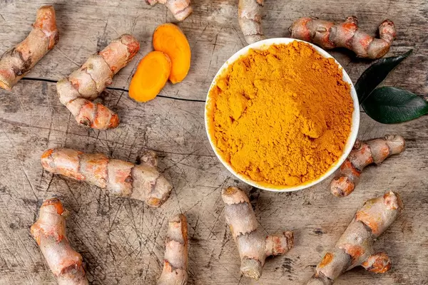 Turmeric powder and turmeric on old wooden background, top view (Flip 2020)