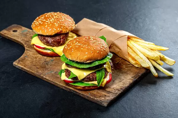 Two burgers and fries on an old kitchen Board (Flip 2019)