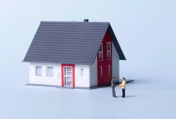Two businessman shaking hands in front a house