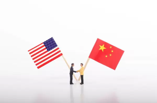 Two businessman shaking hands in front of flags of USA and China