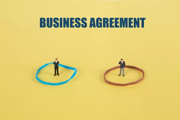 Two businessman standing in cirles and Business Agreement text on yellow backgound
