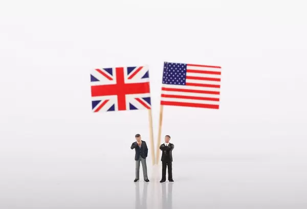 Two businessman standing in front of flags of United Kingdoma and USA