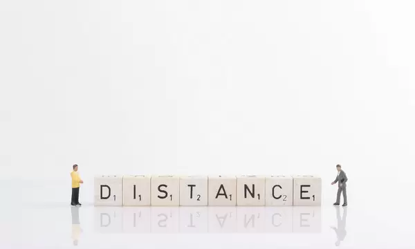 Two businessman standing next to Distance text on wooden blocks