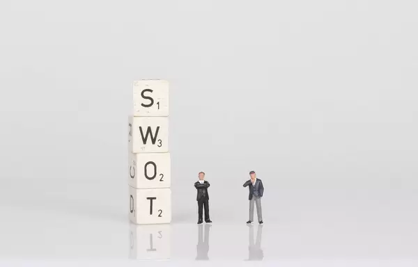 Two businessman standing next to SWOT text