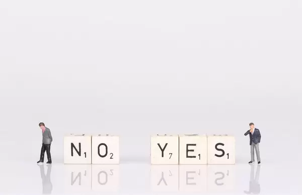Two businessman standing next to yes and no text on wooden blocks