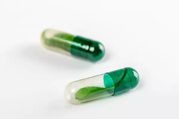 Two capsules with green leaves inside, natural preparations