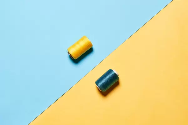 Two colorful spools on colored paper background