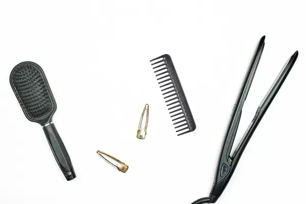 Two comb and electric hair straightener on white