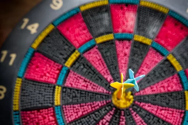 Two Darts pinned in Bullseye of a Colorful Plastic Toy Dart Board