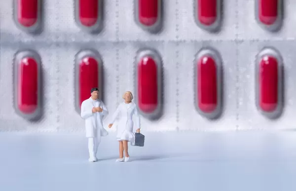 Two doctors with red pills in the background
