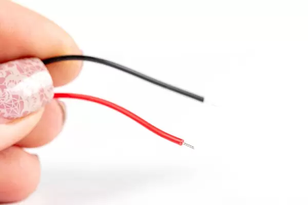 Two electric wires in a woman's hand close up