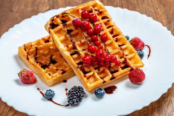 Two fried Belgian waffles with fresh fruit and chocolate syrup (Flip 2019)