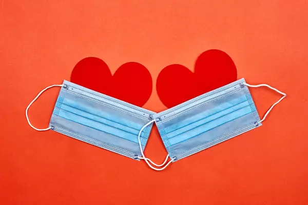 Two heart-shaped paper cuts under protective face masks