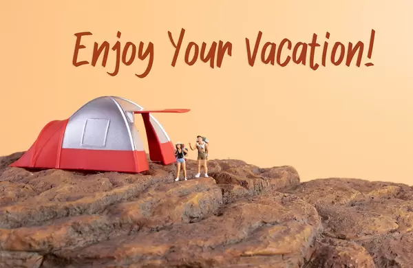 Two hikers standing on rocks and Enjoy your vacation text