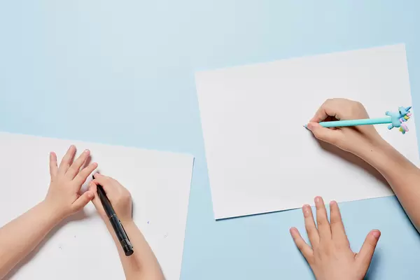 Two little brothers drawing on white paper