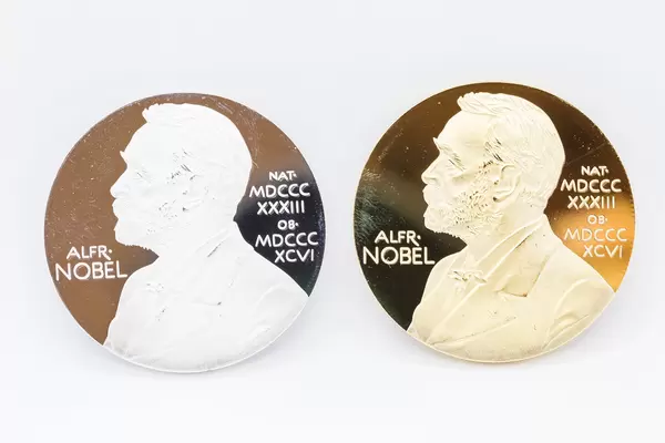 Two medals - one gold, one silver - portraying Swedish chemist Alfred Nobel. Close-up on white background