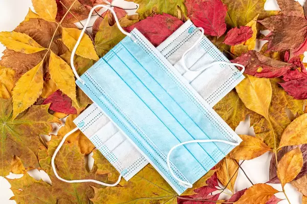 Two medical masks on a background of dry autumn leaves