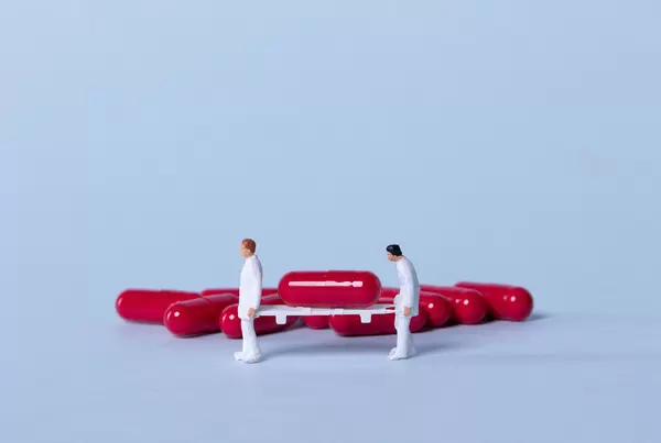 Two medical workers carrying a red pill