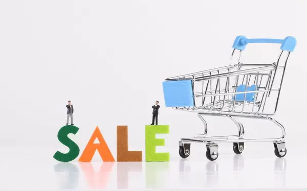 Two miniature businessman with blue shopping cart and Sale text on white background
