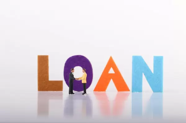 Two miniature businessman with Loan text on white background