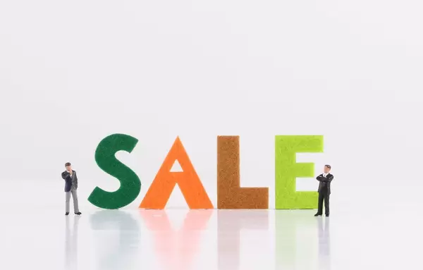 Two miniature businessman with Sale text on white background