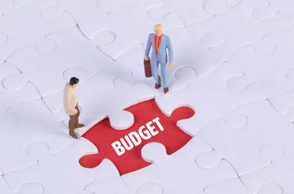 Two miniature man looking at a missing puzzle piece with Budget text