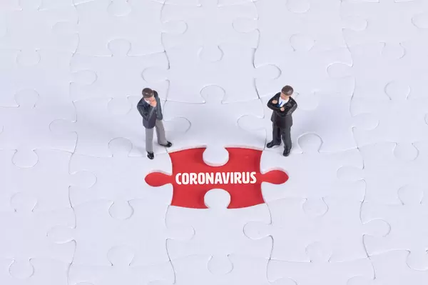 Two miniature man looking at a missing puzzle piece with Coronavirus text