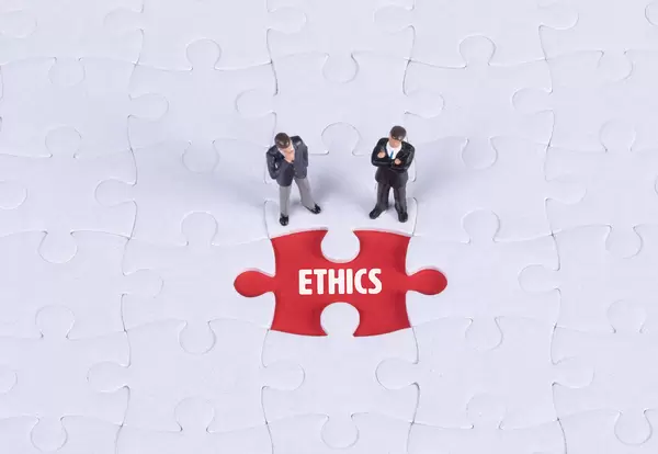 Two miniature man looking at a missing puzzle piece with Ethics text