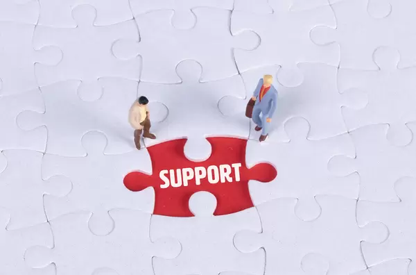 Two miniature man looking at a missing puzzle piece with Support text